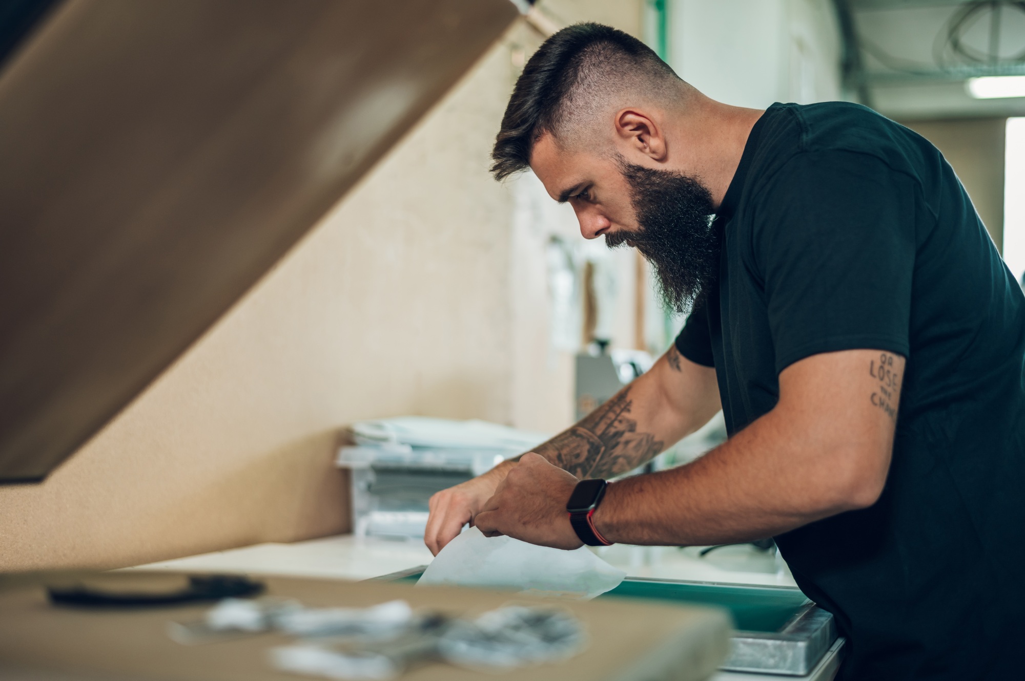 Male worker preparing screen printing film in workshop